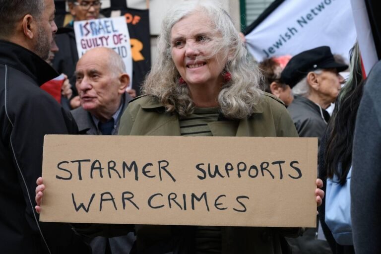A woman holds a placard accusing Labour party leader Sir Keir Starmer of supporting war crimes during a protest called by the International Jewish Anti-Zionist Network