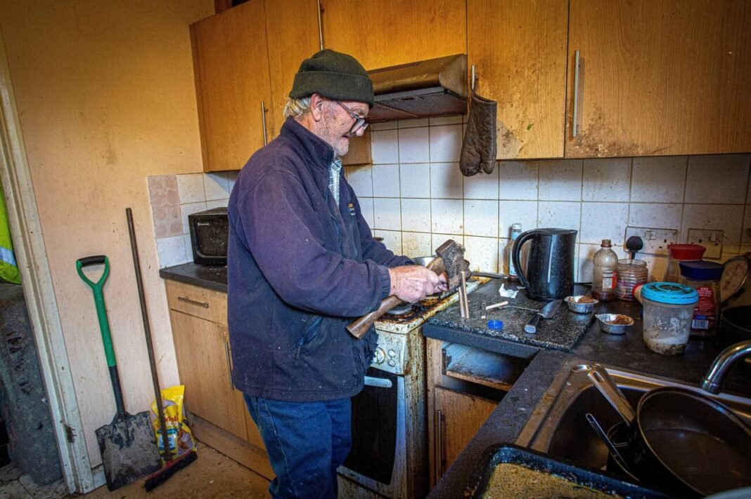 London, UK. Sept 29. Man chops firewood with an axe in his kitchen. Cost of living energy crisis in UK.
