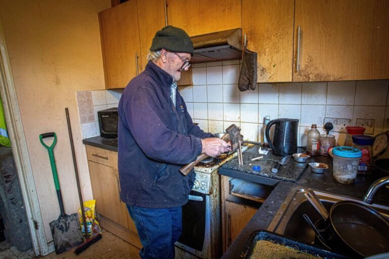 London, UK. Sept 29. Man chops firewood with an axe in his kitchen. Cost of living energy crisis in UK.