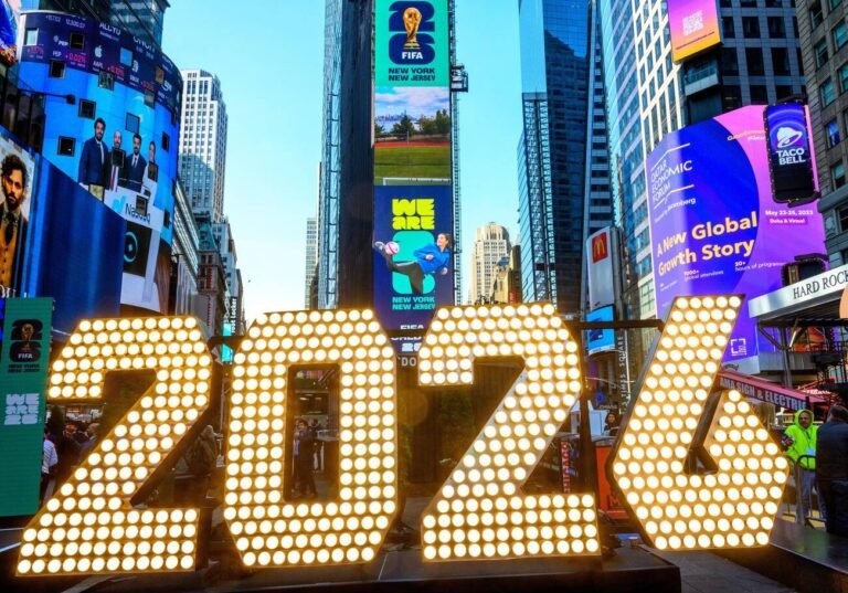 People watch billboards displaying the official logos for the FIFA World Cup 2026 New York at a launch Event in Times Square.